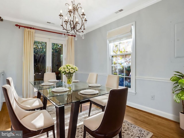 dining space with crown molding, wood finished floors, visible vents, and baseboards