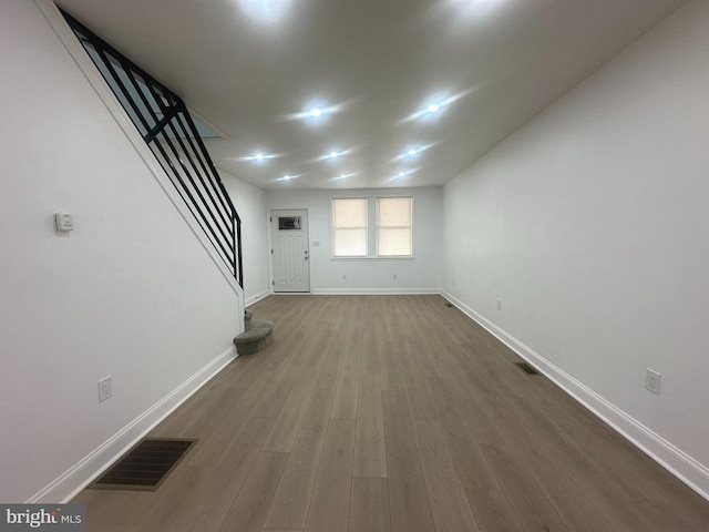 interior space with dark wood-type flooring, visible vents, baseboards, and stairs