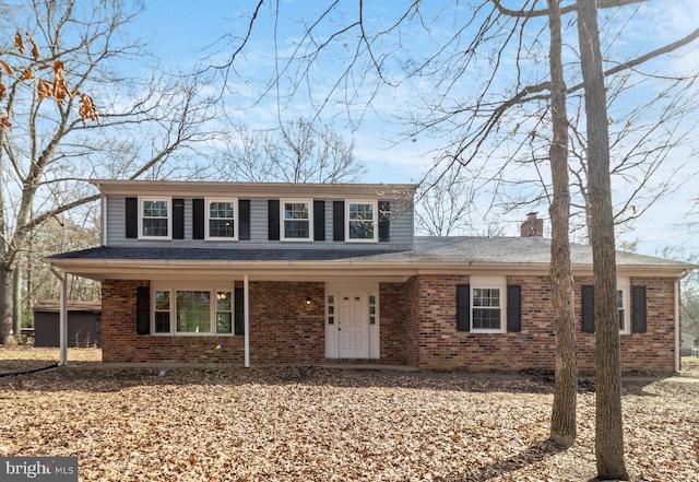 traditional home featuring covered porch, brick siding, and a chimney