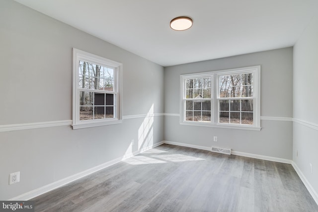 spare room featuring wood finished floors, visible vents, and baseboards