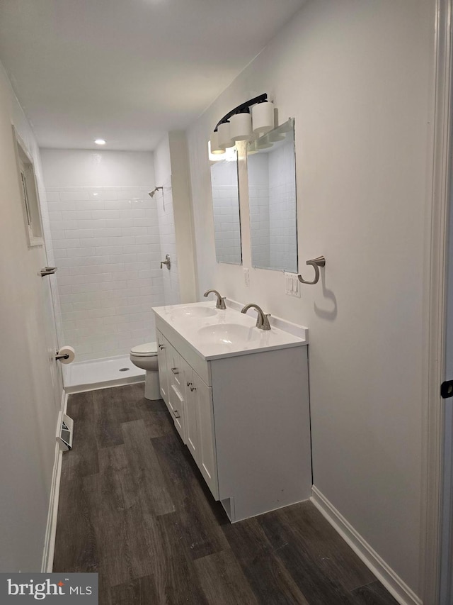 bathroom featuring a stall shower, double vanity, a sink, and wood finished floors