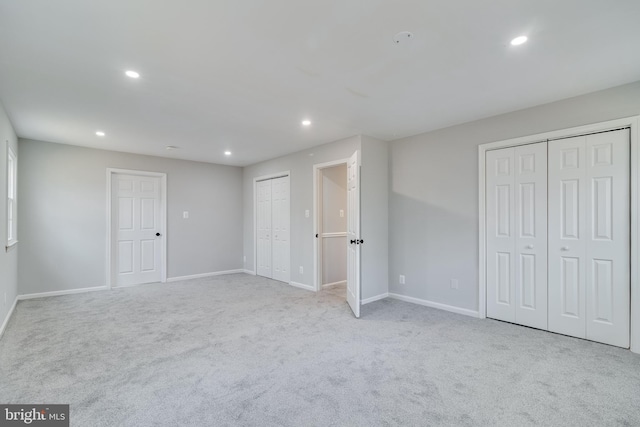 unfurnished bedroom featuring multiple closets, carpet, baseboards, and recessed lighting