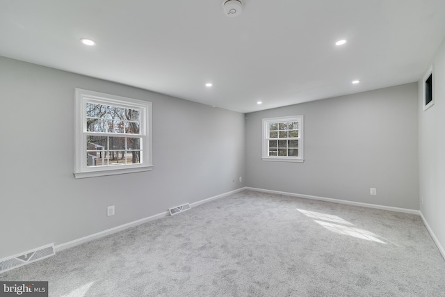 carpeted empty room featuring baseboards, visible vents, and recessed lighting