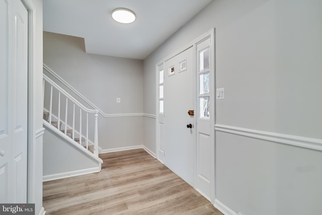 foyer entrance featuring stairway, baseboards, and wood finished floors