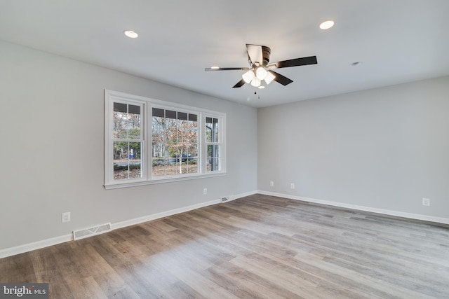 empty room featuring recessed lighting, wood finished floors, visible vents, and baseboards