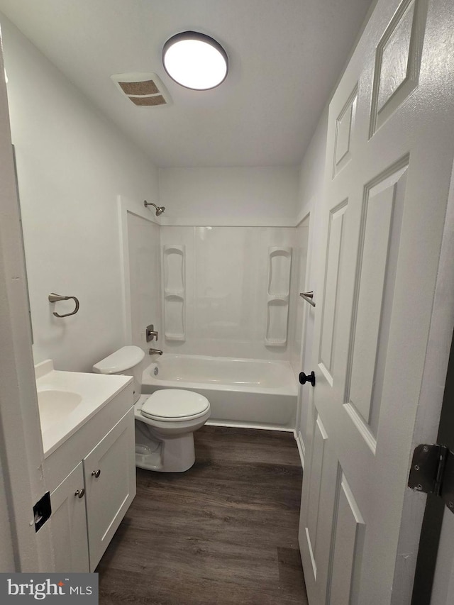 bathroom with toilet, wood finished floors, vanity, visible vents, and shower / bathing tub combination