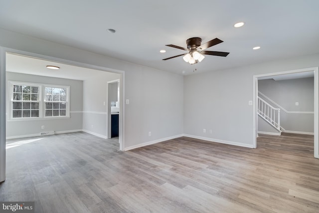 empty room featuring stairs, baseboards, and wood finished floors