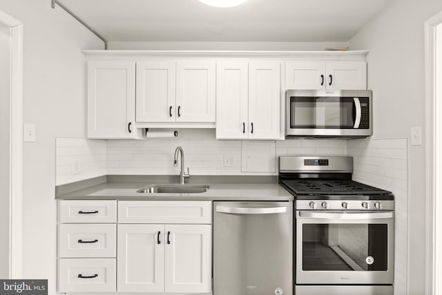 kitchen with appliances with stainless steel finishes, white cabinetry, a sink, and tasteful backsplash