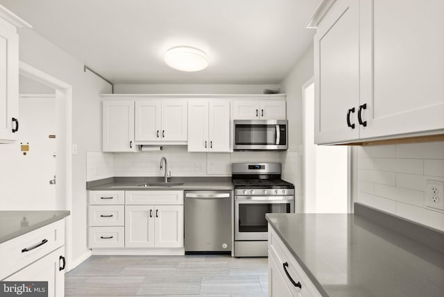 kitchen featuring stainless steel appliances, a sink, white cabinetry, and decorative backsplash