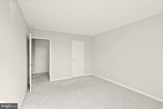 unfurnished bedroom featuring light carpet and baseboards