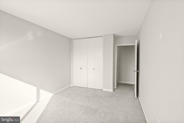 unfurnished bedroom with a closet, carpet flooring, and baseboards