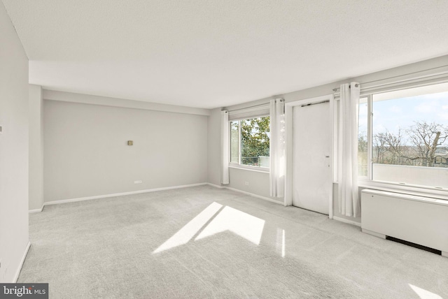 carpeted empty room with baseboards and radiator heating unit