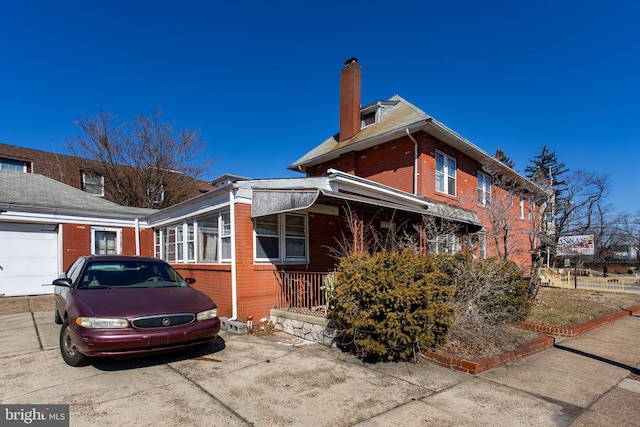 view of side of home featuring driveway, brick siding, and a chimney