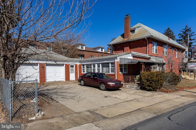 view of front of property with concrete driveway, brick siding, a chimney, and an attached garage