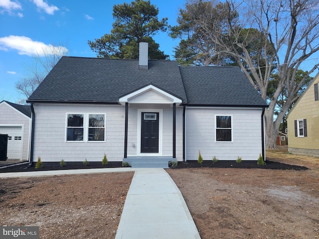 ranch-style home with roof with shingles and a chimney