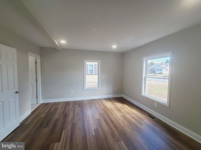 unfurnished room featuring dark wood-type flooring, visible vents, and baseboards