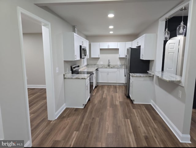 kitchen with white cabinets, dark wood-style floors, appliances with stainless steel finishes, light stone countertops, and a sink