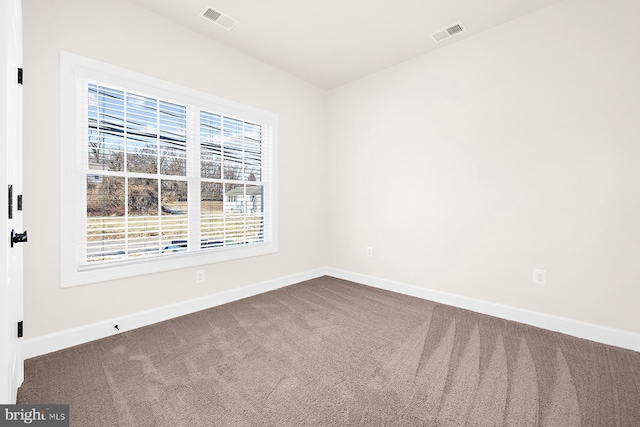 carpeted spare room with visible vents and baseboards