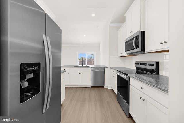 kitchen featuring tasteful backsplash, white cabinets, appliances with stainless steel finishes, ornamental molding, and a sink