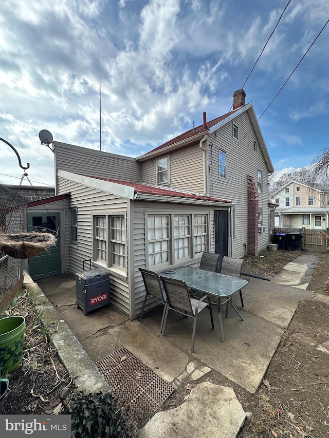 back of house with a chimney, fence, outdoor dining area, and a patio