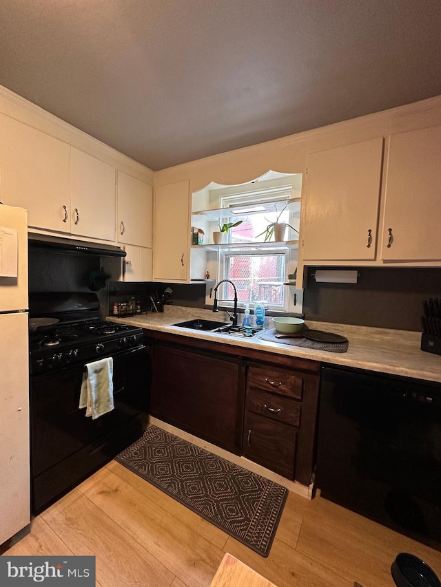 kitchen with light countertops, white cabinets, a sink, under cabinet range hood, and black appliances