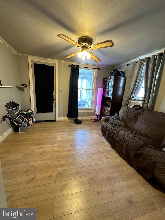 living room featuring a ceiling fan, cooling unit, baseboards, and light wood finished floors