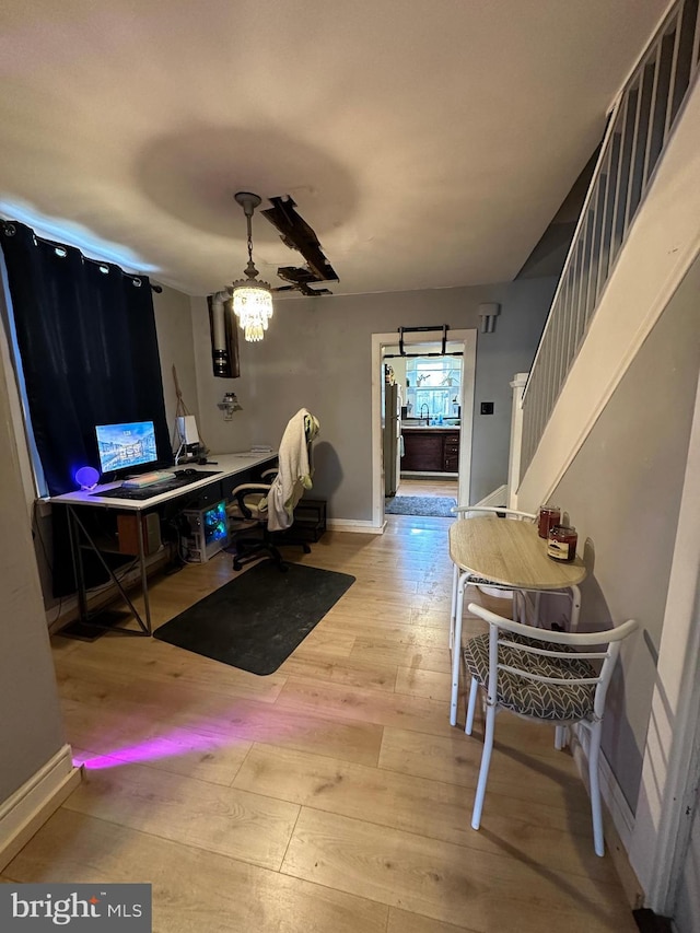 dining area with a chandelier, hardwood / wood-style floors, stairway, and baseboards