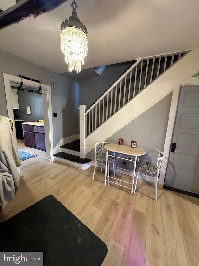 foyer entrance featuring baseboards, stairway, an inviting chandelier, and wood finished floors