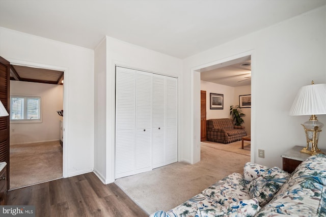 unfurnished bedroom featuring dark wood-style floors, a closet, dark carpet, and baseboards