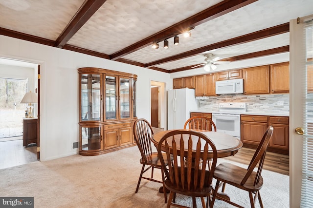 dining area with light carpet, a ceiling fan, baseboards, and beamed ceiling