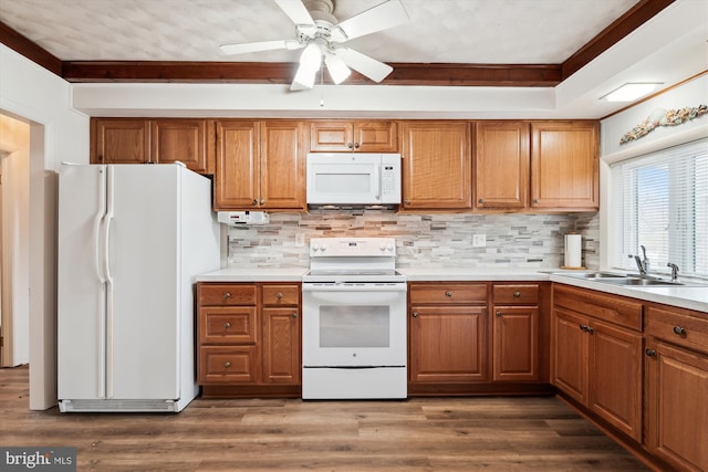 kitchen featuring dark wood-style flooring, brown cabinets, backsplash, a sink, and white appliances