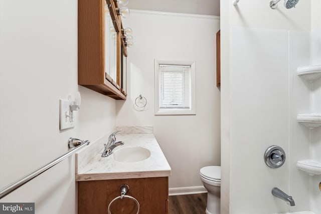 bathroom with toilet, wood finished floors, vanity, baseboards, and shower / washtub combination