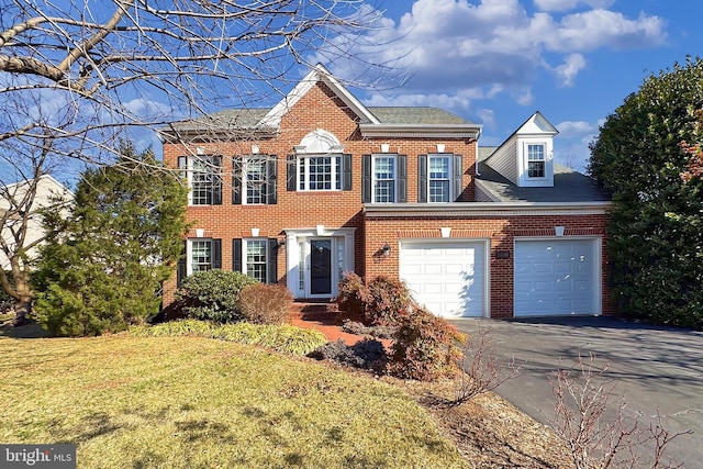 view of front facade featuring driveway, an attached garage, a front lawn, and brick siding