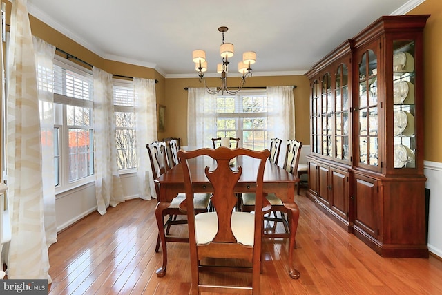 dining space with ornamental molding, light wood finished floors, a chandelier, and baseboards