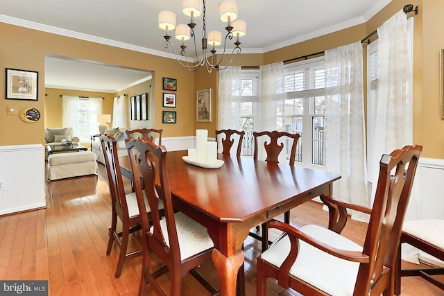 dining space featuring a chandelier, wood-type flooring, a healthy amount of sunlight, and crown molding