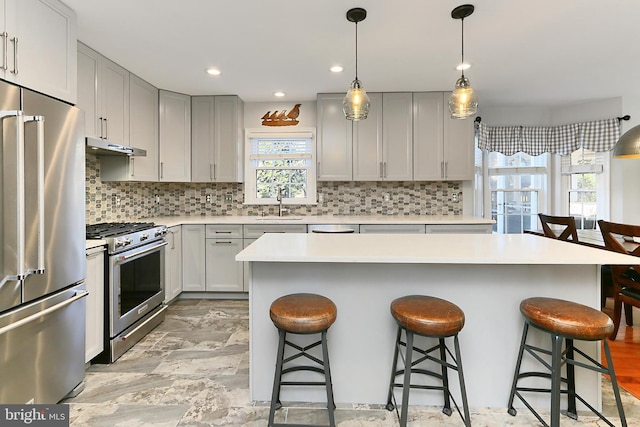 kitchen featuring decorative backsplash, a breakfast bar area, stainless steel appliances, and a sink