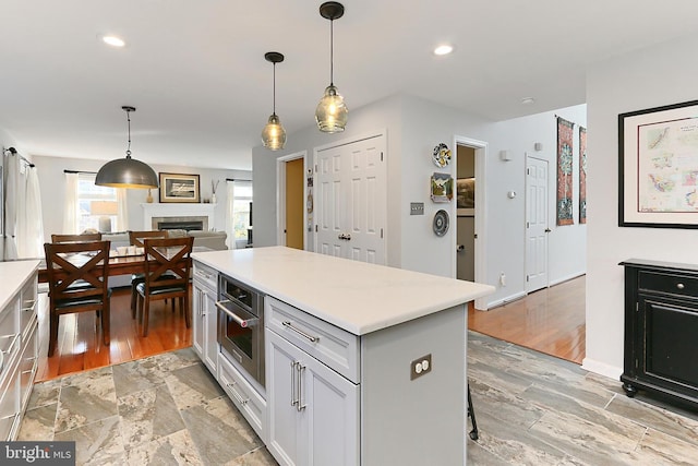 kitchen with recessed lighting, stainless steel oven, light countertops, a center island, and decorative light fixtures