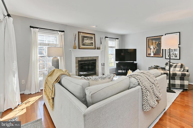 living area featuring light wood-style floors, a fireplace, and baseboards