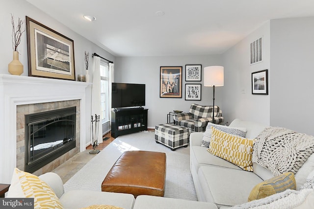 living area featuring carpet floors, baseboards, visible vents, and a tiled fireplace