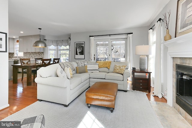 living area with a tiled fireplace, light wood-style flooring, and recessed lighting