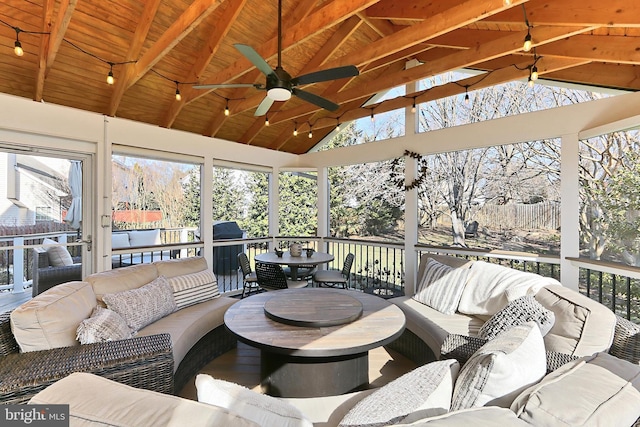 sunroom with vaulted ceiling with beams, a wealth of natural light, wooden ceiling, and a ceiling fan