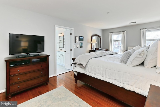 bedroom featuring a sink, wood finished floors, visible vents, baseboards, and ensuite bath