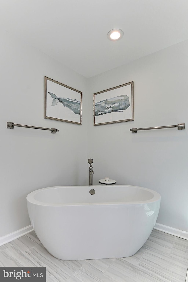 full bath featuring a soaking tub and baseboards