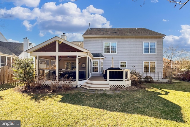 rear view of property with a chimney, a lawn, a sunroom, fence, and a wooden deck