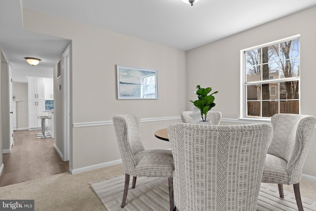 carpeted dining room with baseboards