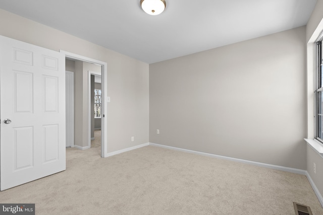 unfurnished bedroom with baseboards, multiple windows, visible vents, and carpet flooring