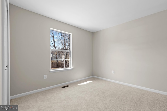 empty room featuring carpet floors, visible vents, and baseboards