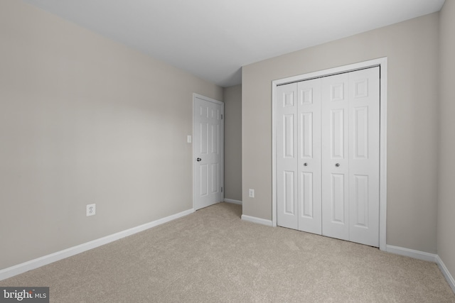 unfurnished bedroom with carpet, baseboards, and a closet