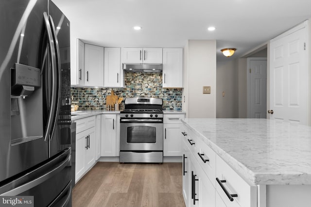 kitchen featuring light wood-style flooring, under cabinet range hood, refrigerator with ice dispenser, backsplash, and stainless steel range with gas cooktop