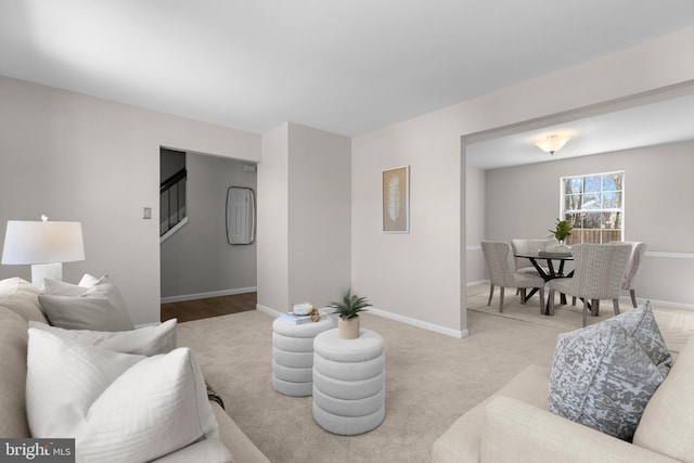 living area with carpet, stairway, and baseboards